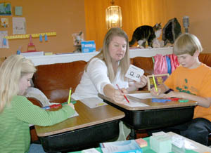 Parent Jenna Hathaway Ewart teaches her children Arran, 8, and Alana, 6, at their home. Aladdin the cat looks on. PHOTO BY DAVID ROBERT